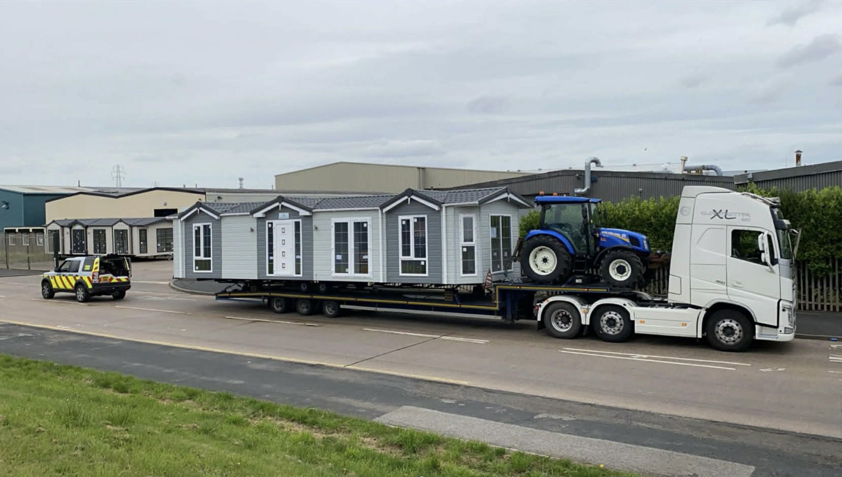 Volvo Globetrotter with modular home and New Holland tractor on trailer — oversized load transport