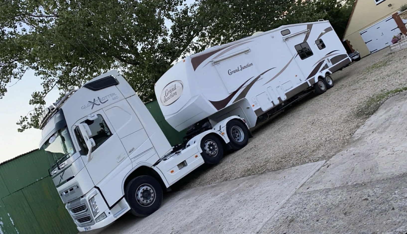 White Volvo semi-truck towing Grand Junction fifth-wheel luxury travel trailer