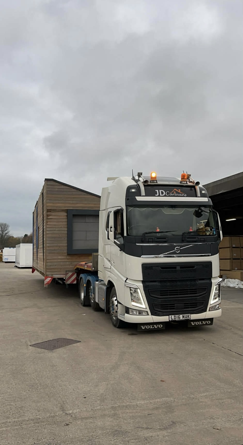 JD Caravans Volvo FH carrying wooden lodge style mobile home on low loader